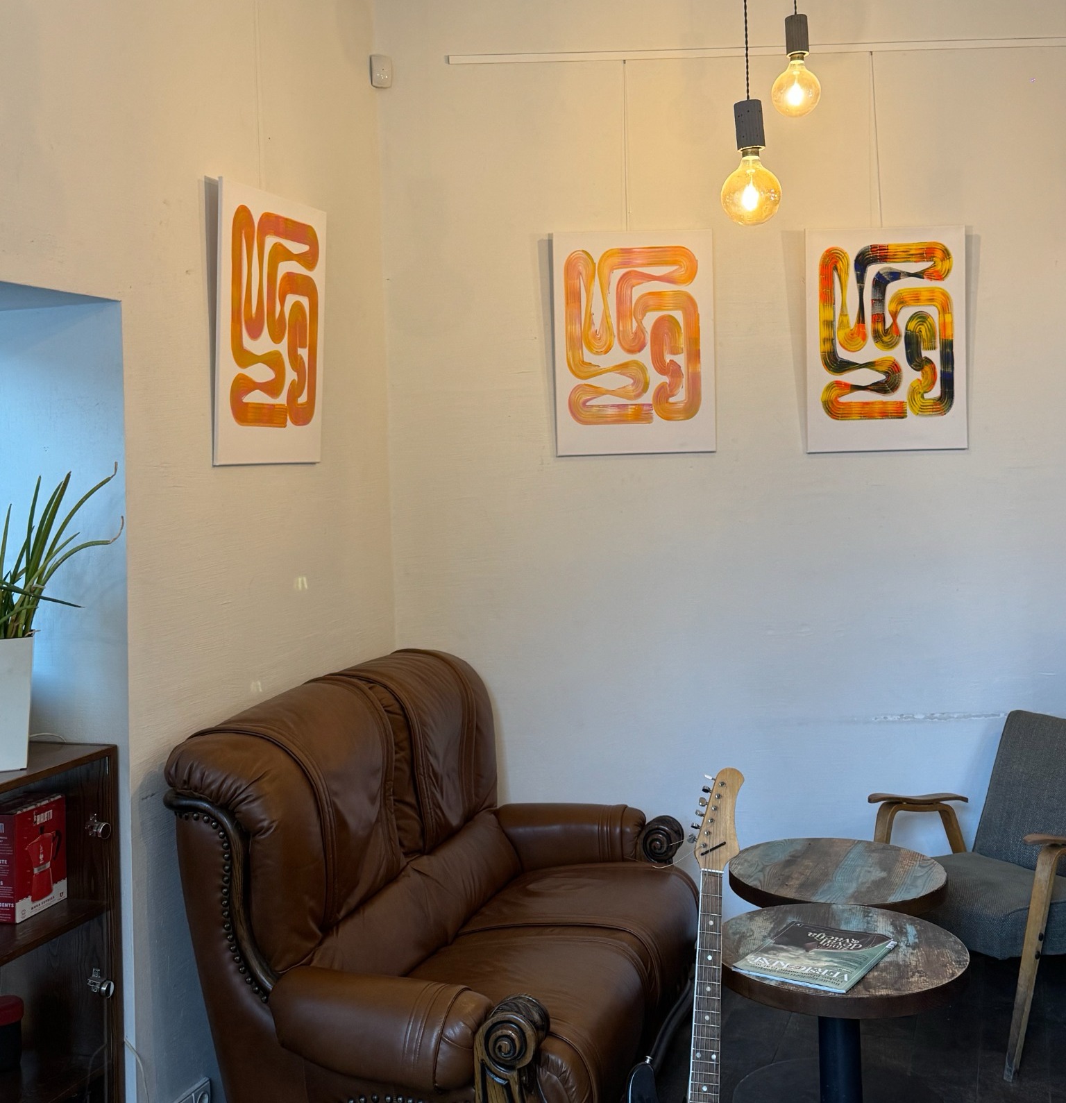 Three Lineage Blanc paintings displayed on a wall at Elska Coffee in Vilnius