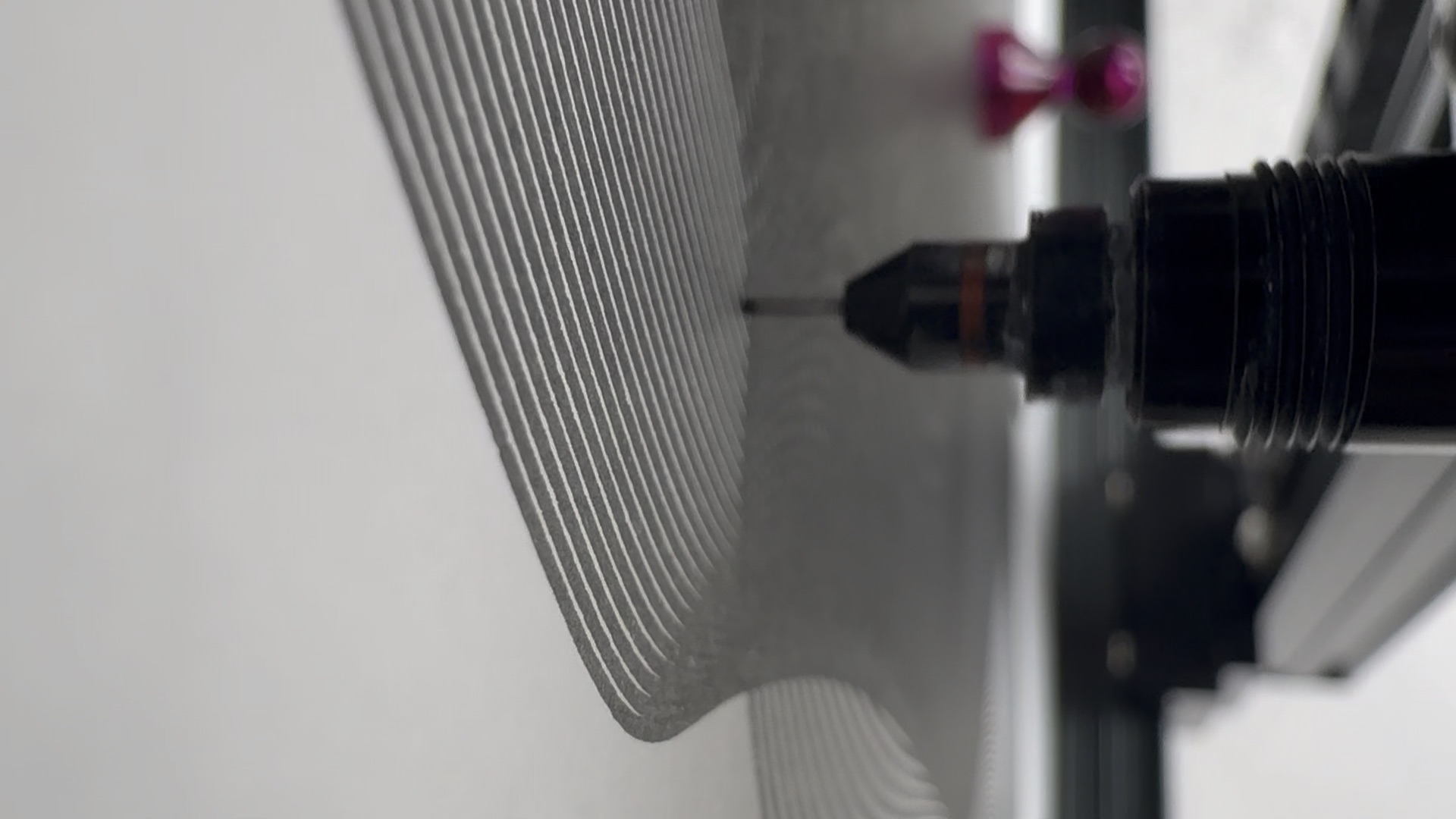 Close-up of a plotter pen drawing black lines on white paper